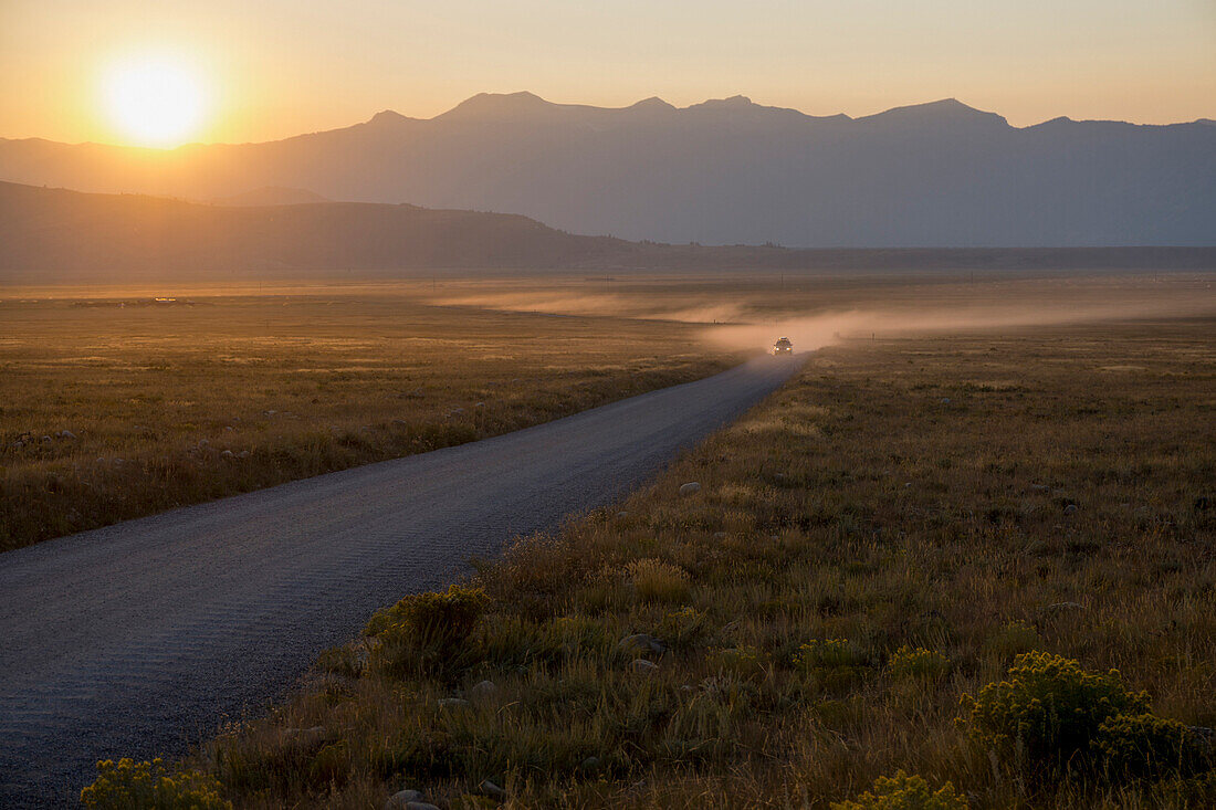 Car on dusty road at sunset, Grand Teton Park, Wyoming, United States of America, North America