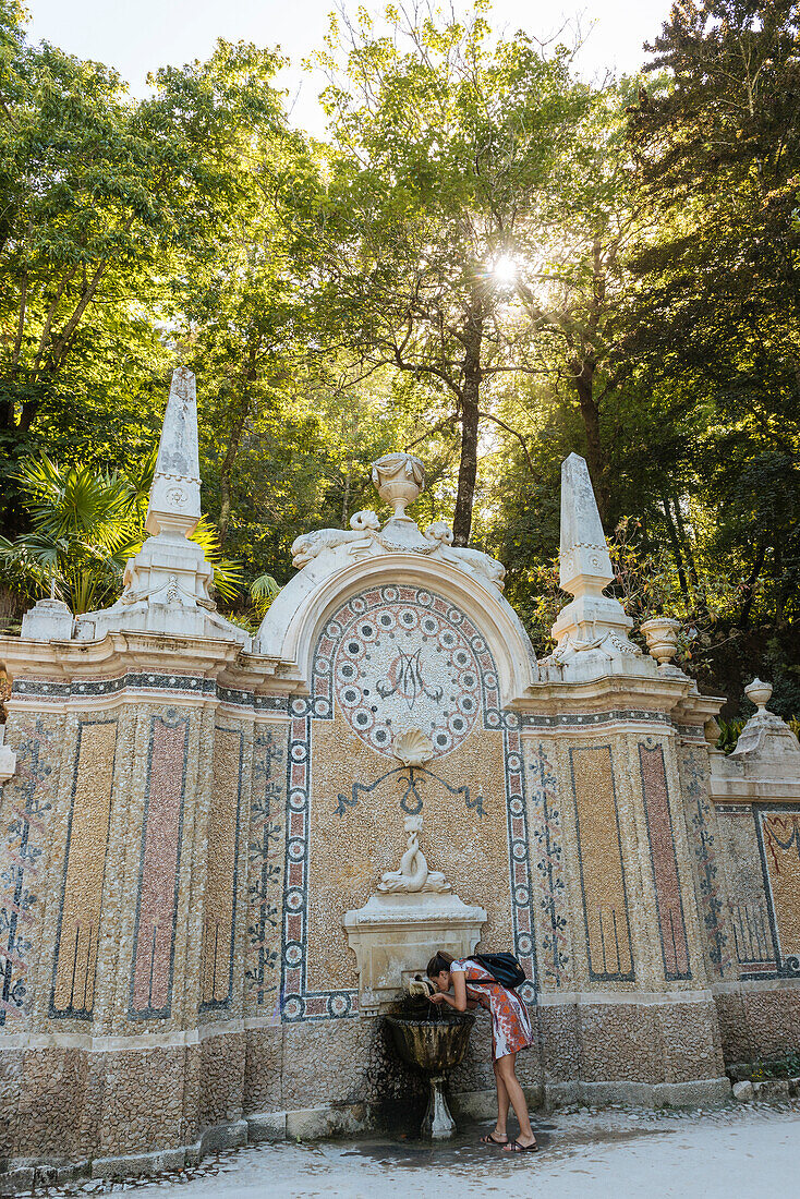 Woman using water fountain, Quinta da Regaleira, Sintra, Portugal, Europe