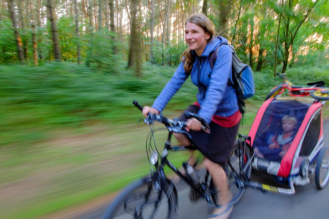 Mother with child trailer biking on a forest path, Usedom, Ostseeküste, Mecklenburg-Vorpommern, Germany