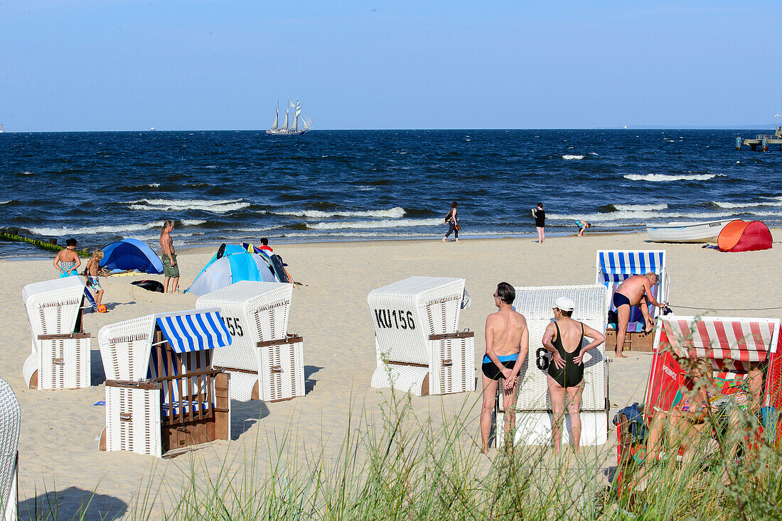 Menschen und Strandkörbe am Strand, Dreimaster im Hintergrund,  Bansin, Usedom, Ostseeküste, Mecklenburg-Vorpommern,  Deutschland