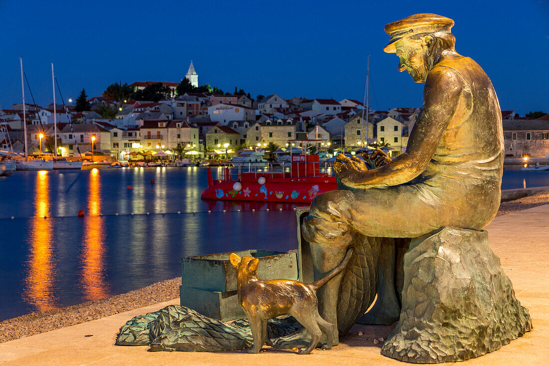 Fisherman statue with view to the old town of Primosten in the background, Croatia, Europe