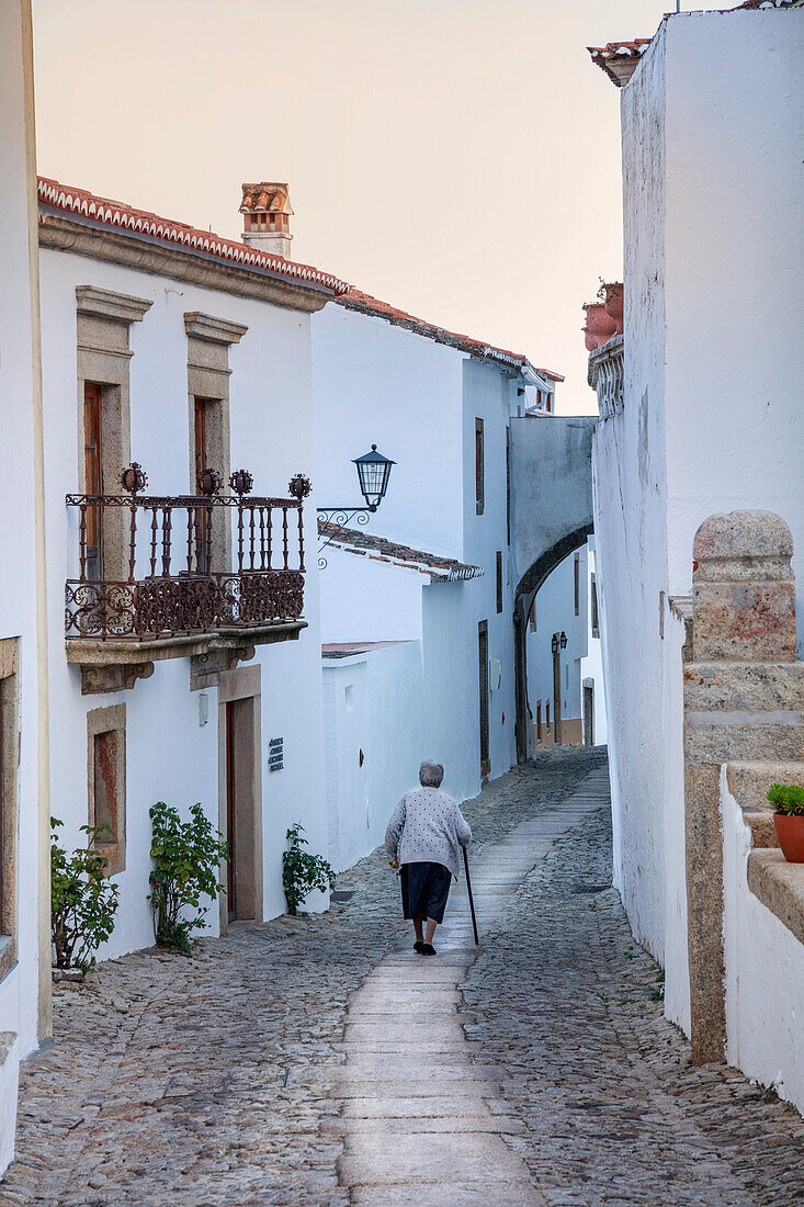 An old woman walking along an alley in the mountain village of Marvao in the Alentejo, Portugal, Europe
