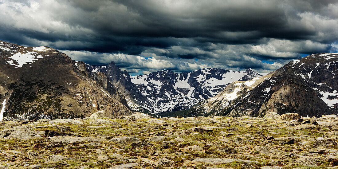 Snow capped mountains and a dramatic cloudy sky in the Rocky Mountain National Park, Colorado.