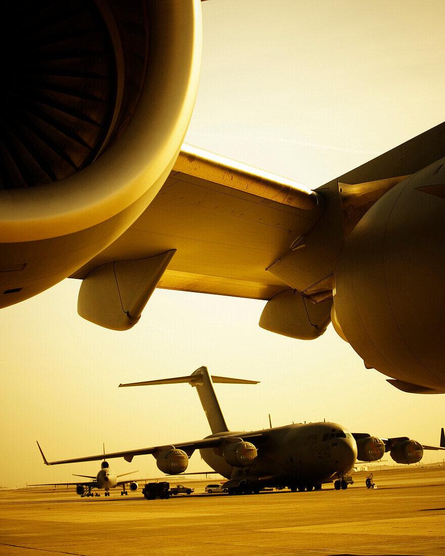 Close up of jet engines with a cargo planes in the background.