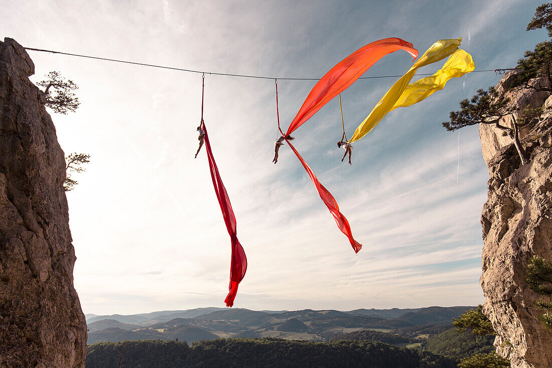 Female aerial silk gymnasts performing between two cliffs 30 meters above ground, Lower Austria, Austria