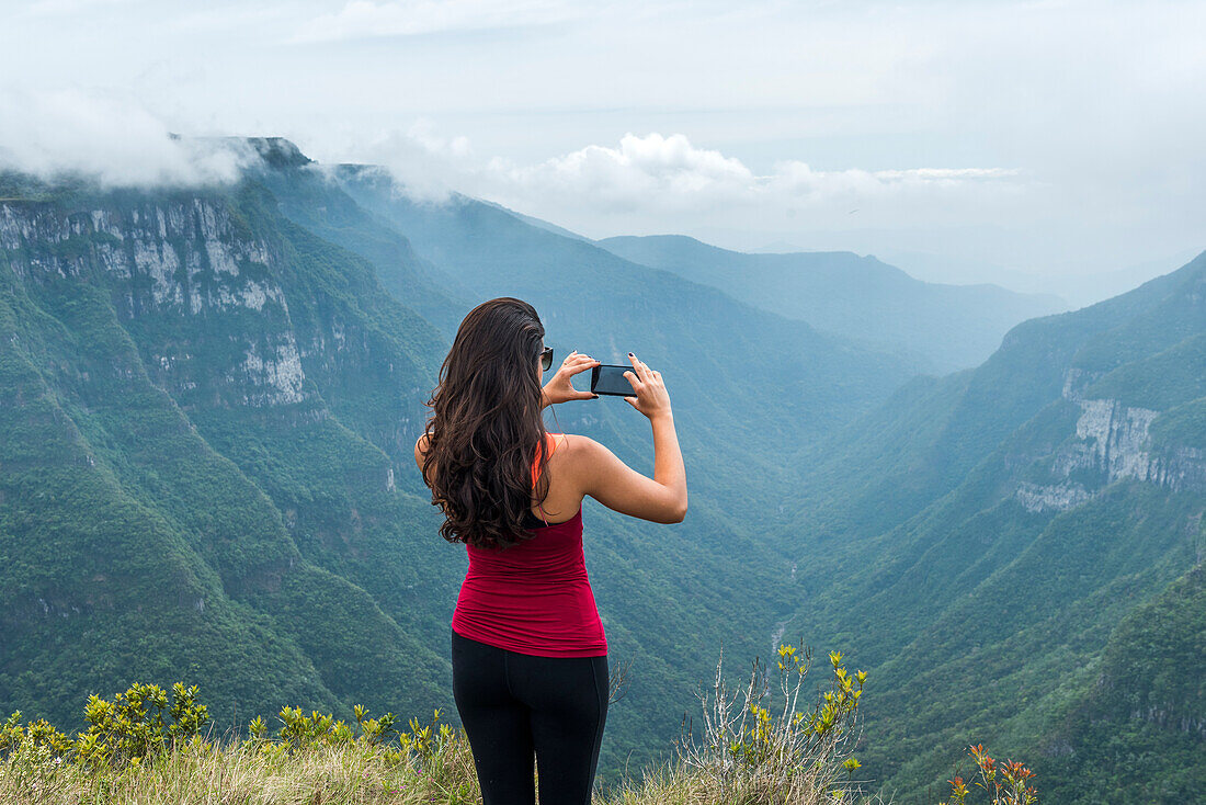 Young woman photographing in Canion Fortaleza, Cambara do Sul, Rio Grande do Sul, Brazil