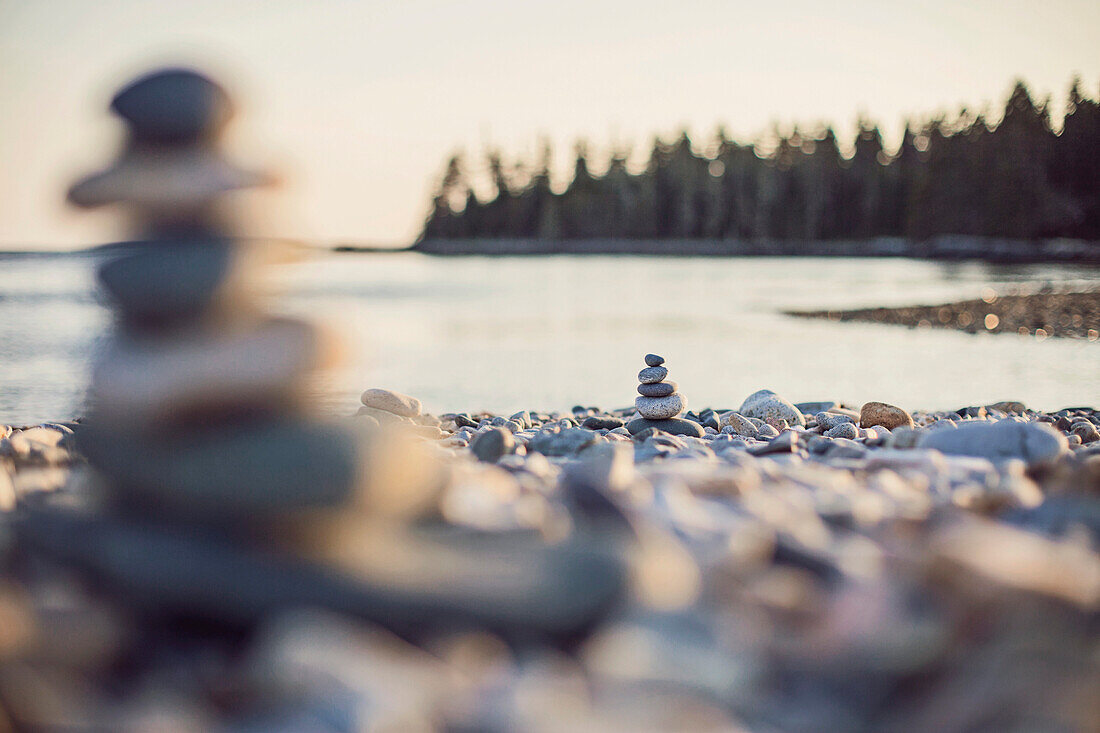 Cairns stand on a rocky beach at sunset in Maine's Acadia National Park