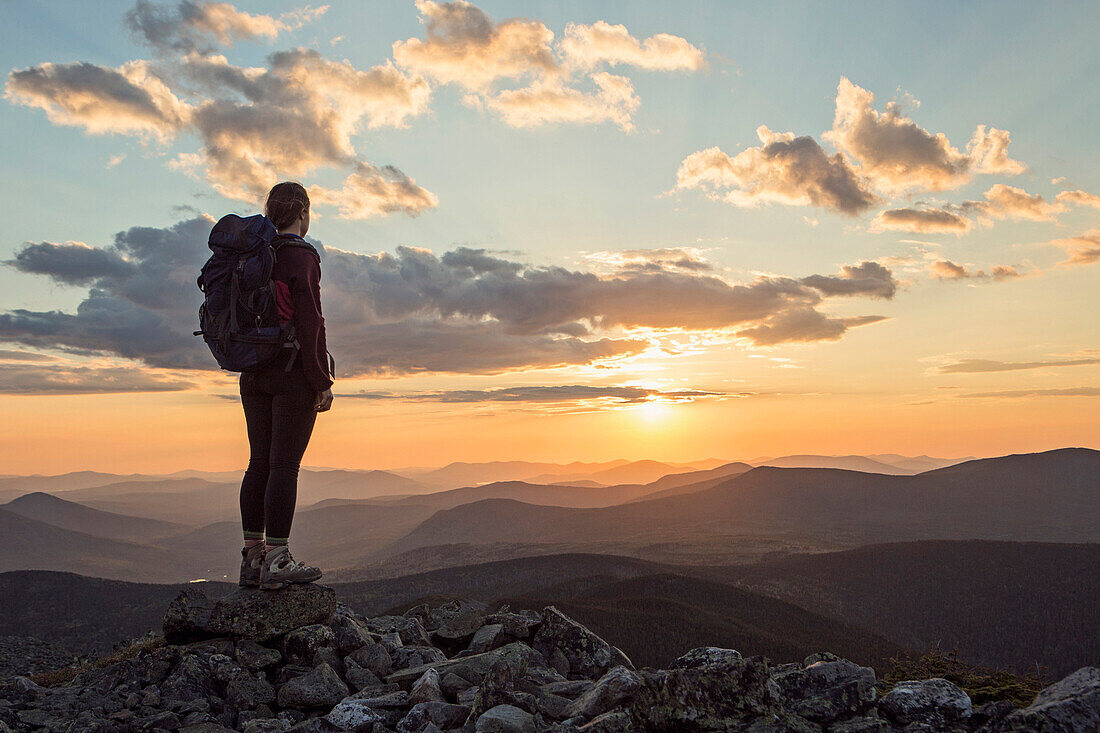 Female hiker admiring scenic sunset from top of Mount Abraham, Maine, USA