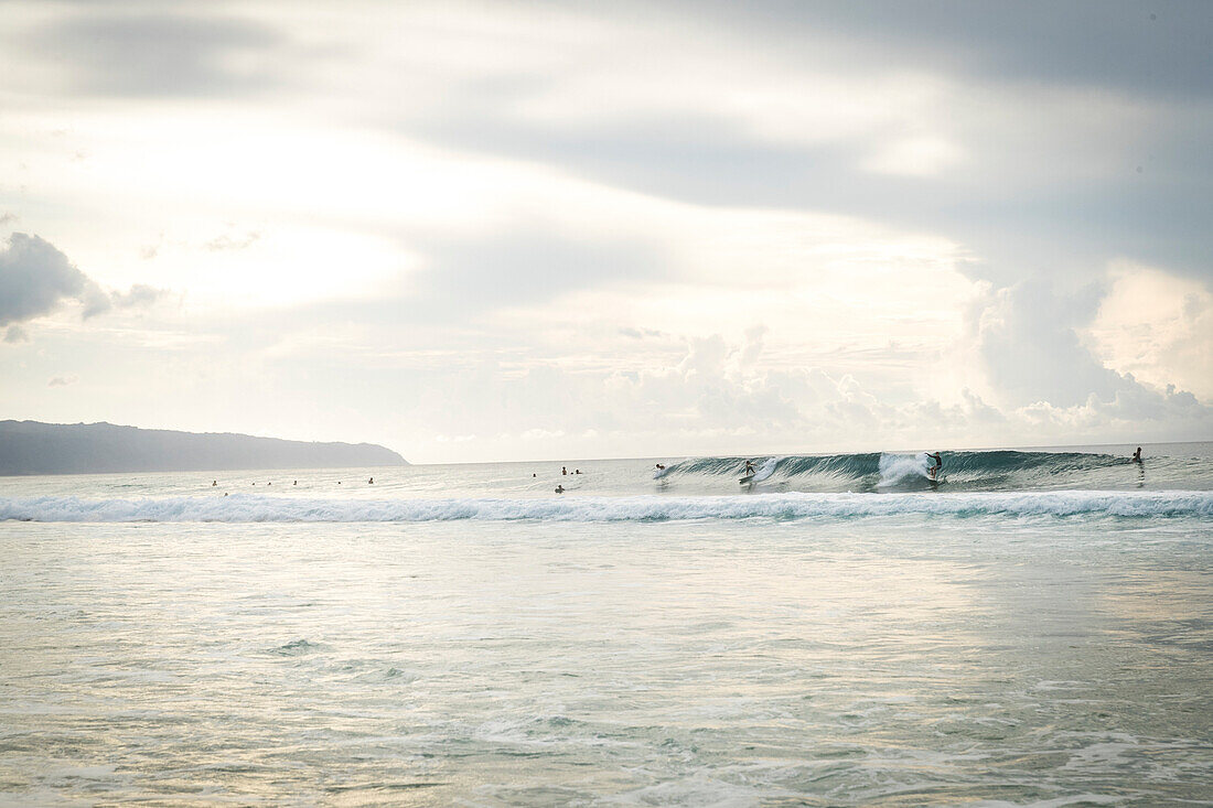 Surfers riding wave in Pacific Ocean, Oahu, Hawaii Islands, USA