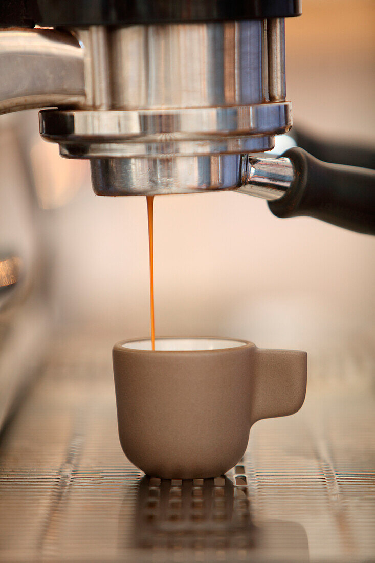 Espresso coffee pouring from coffee maker into cup, Oakland, California, USA