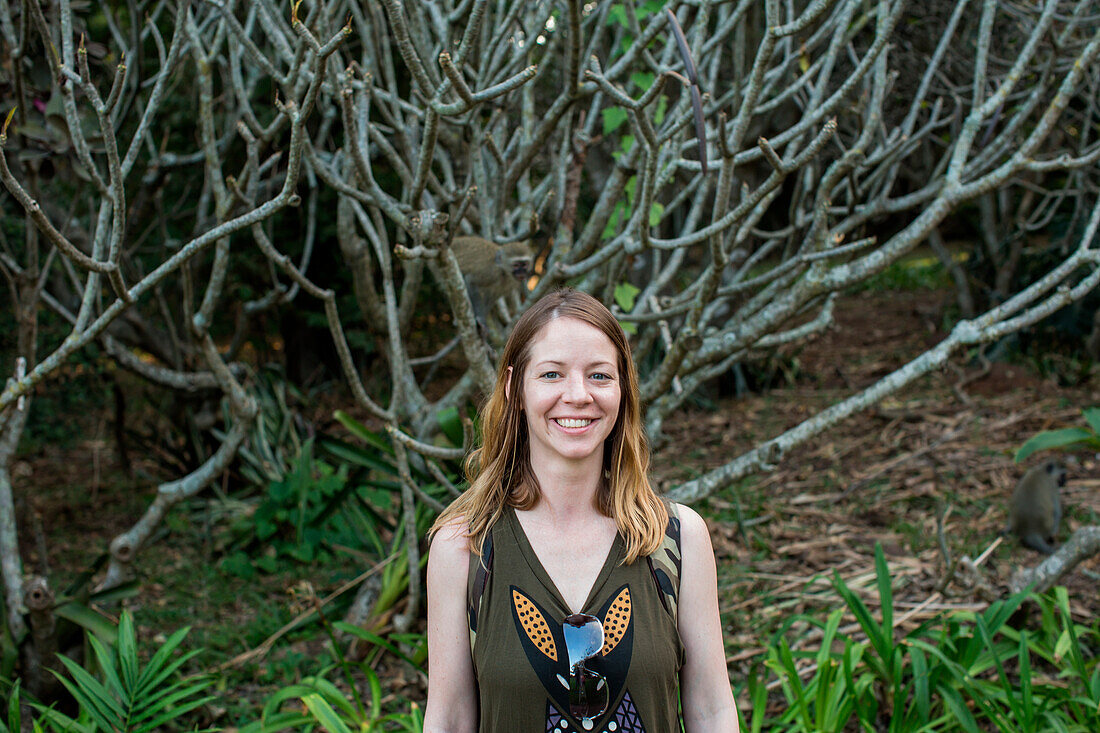 Woman standing against Indian banyan tree (Ficus benghalensis) at Durban Botanic Gardens in Durban, KwaZulu-Natal, South Africa