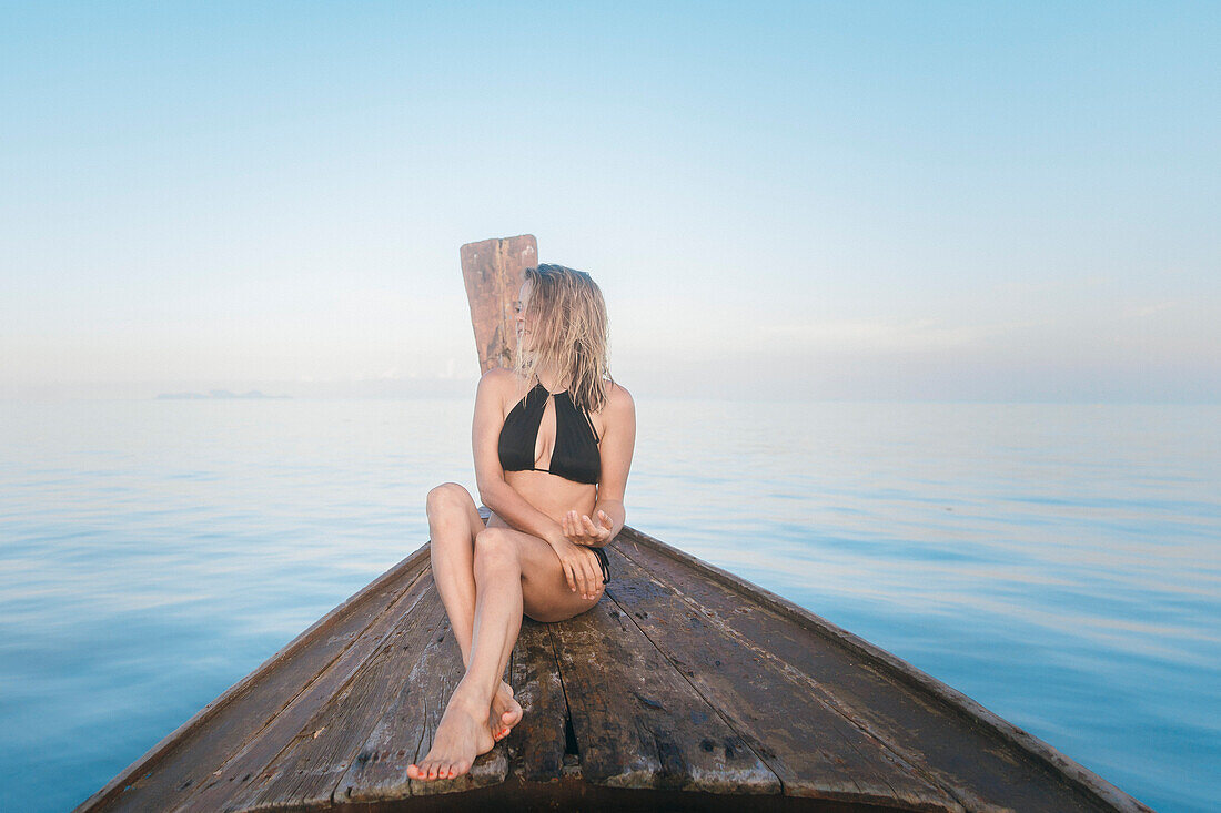 Woman in bikini sitting on prow of Thai rowboat, Tambon Ko Tarutao, Chnag Wat Krabi, Thailand