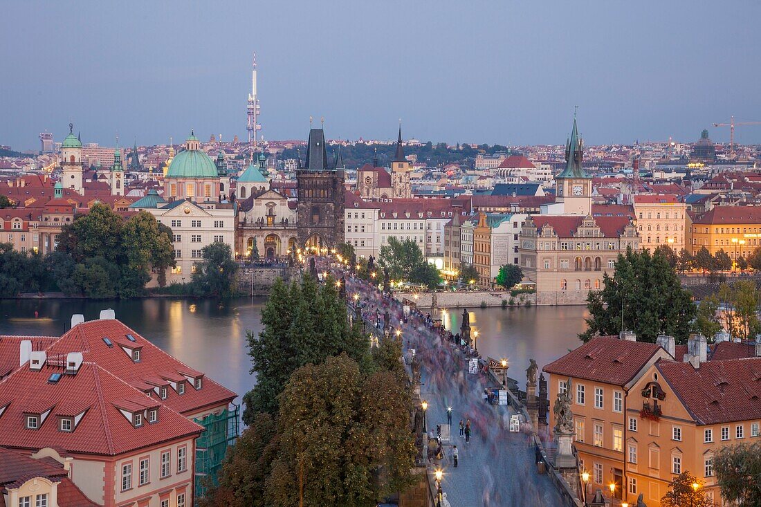 Dusk in Prague old town, Czech Republic. Crowd of tourists on Charles Bridge across Vltava river.