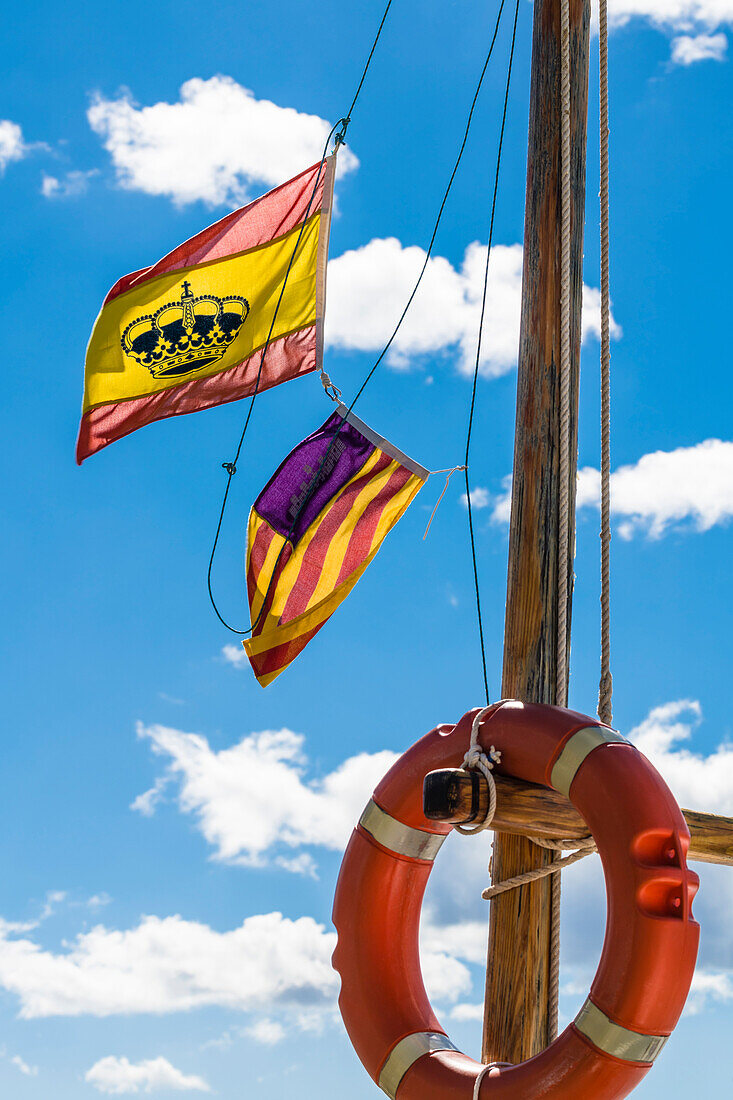Spanish flags on a fishing boat with life ring in the harbour, Port d'Alcudia, Mallorca, Spain