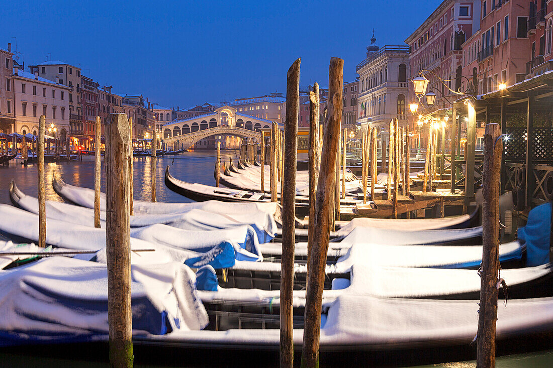 Rialto Bridge with snow-covered gondolas at dusk after a snowfall, Grand Canal, Venice, Veneto, Italy