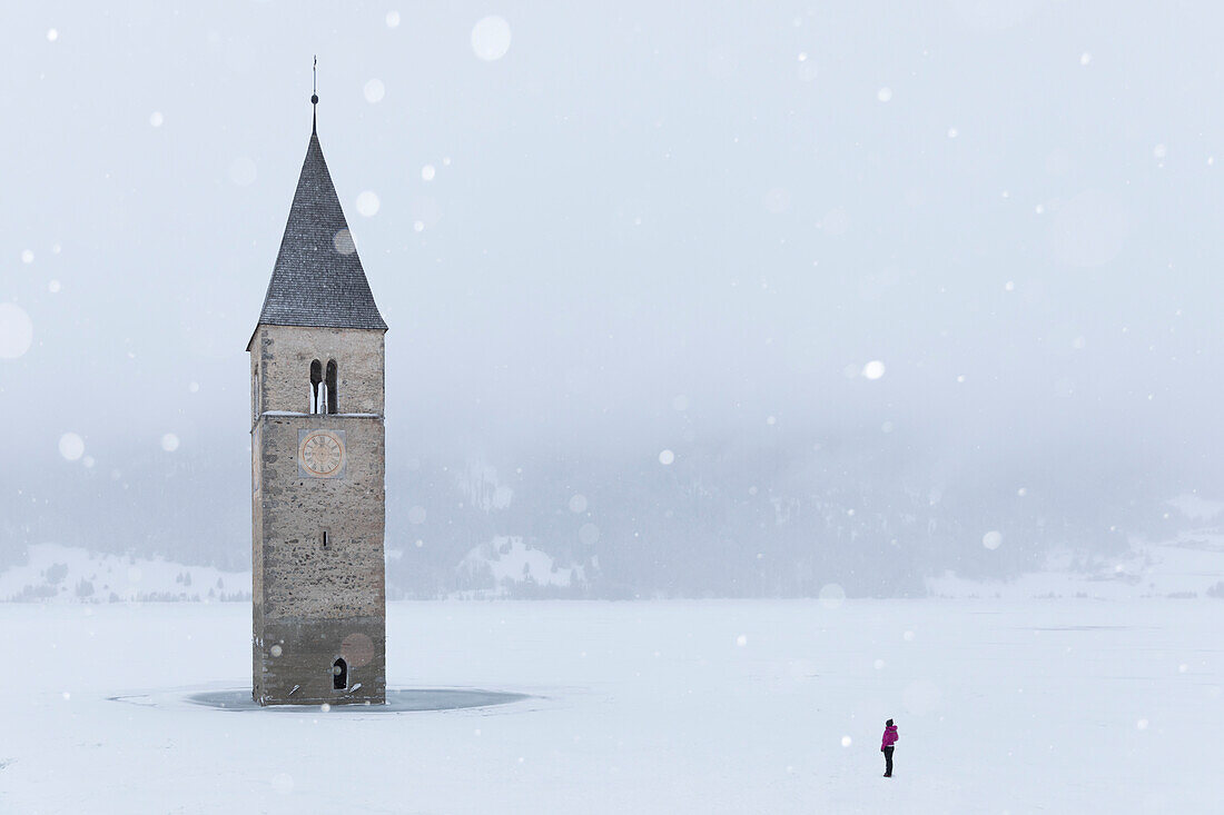 The submerged bell tower of Curon Venosta, province of Bolzano, Alto Adige district, Italy, under a snowfall