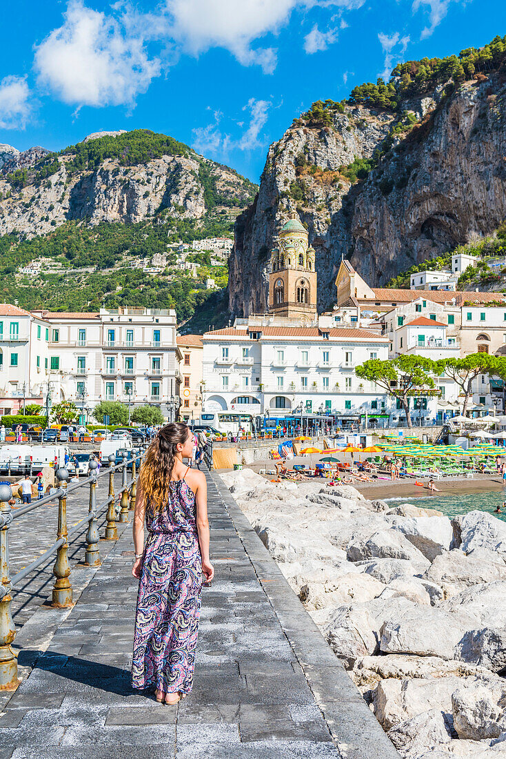 Amalfi, Amalfi coast, Salerno, Campania, Italy. Young woman strolling along the pier of Amalfi village