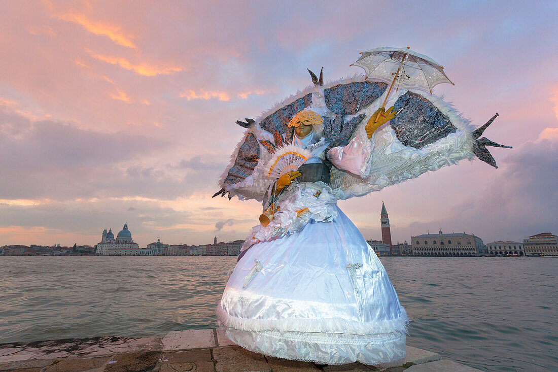 Typical mask of Carnival of Venice at San Giorgio island with Church of Santa Maria della Salute and San Marco Bell Tower on background, Venice, Veneto, Italy
