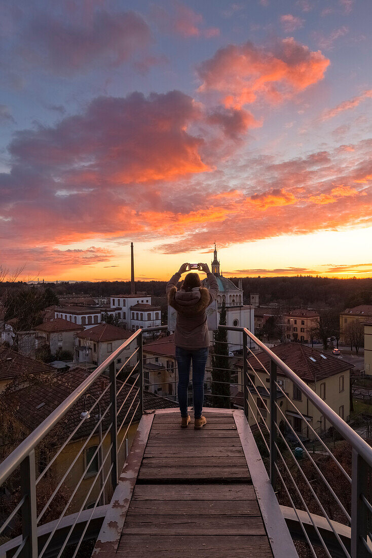 A turist taking a picture during a sunset at the balcony over the model worker village of Crespi d'Adda, Unesco World Heritage Site. Capriate San Gervasio, Bergamo province, Lombardy, Italy.