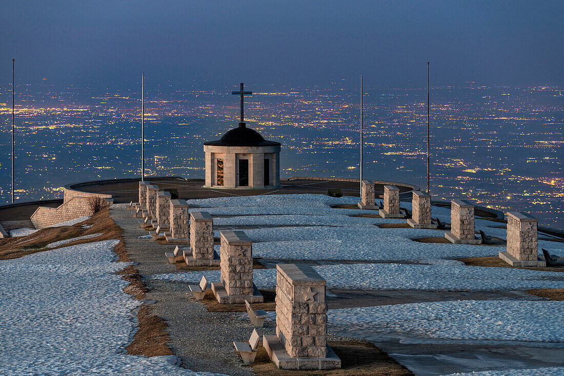 Monte Grappa, province of Vicenza, Veneto, Italy, Europe. On the summit of Monte Grappa there is a military memorial monument. In the background the lights of the Venetian Plain