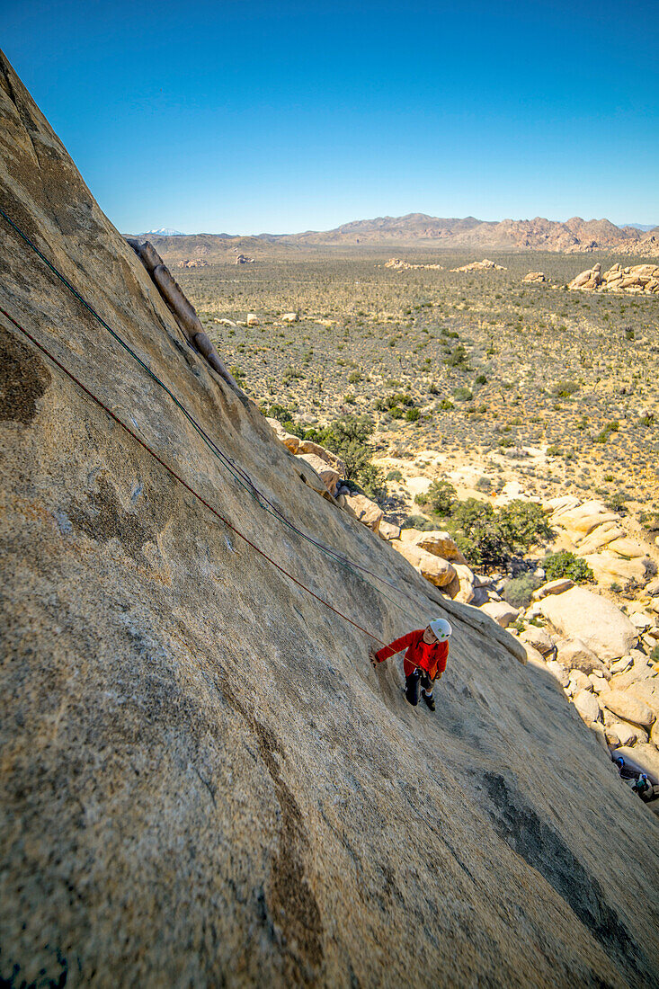 A young boy climbing a technical rock climb in Joshua Tree National Park, California.