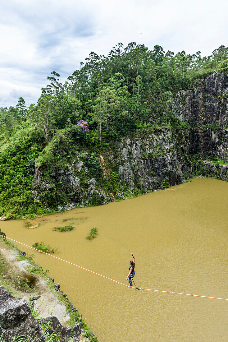 View from above of adventurous female slackliner balancing on rope, Dibs Quarry, Maripora, Sao Paulo State, Brazil