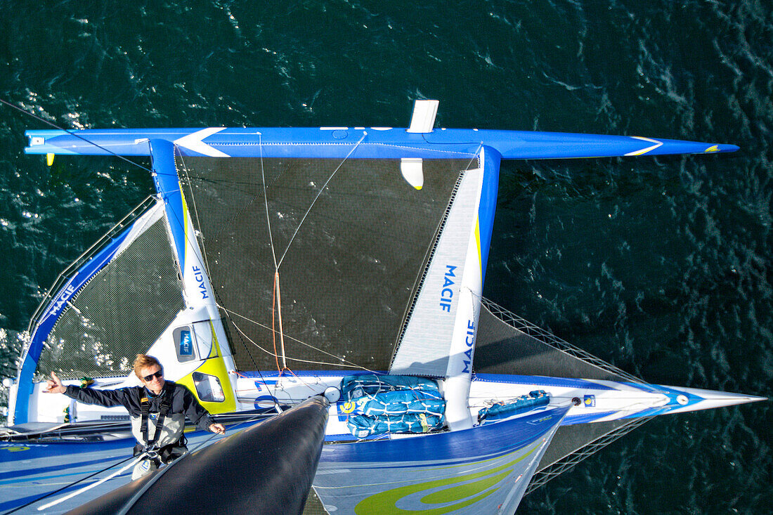 View from top of mast of trimaran with sailor climbing, Atlantic Ocean, Brittany, France