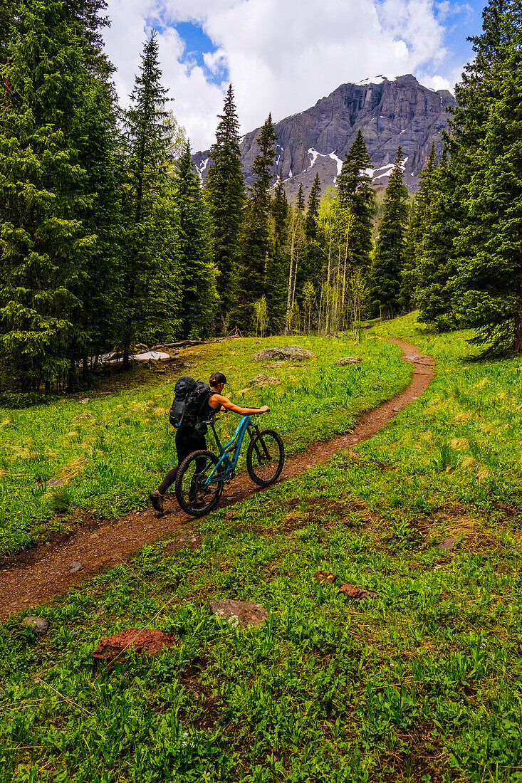 Female biker pushing mountain bike up Ice lakes Trail, Colorado, USA