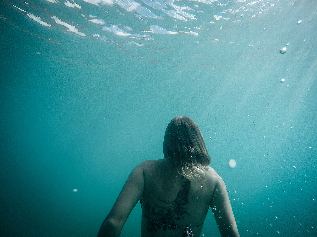 Rear view of woman swimming underwater, St. John, US Virgin Islands, USA