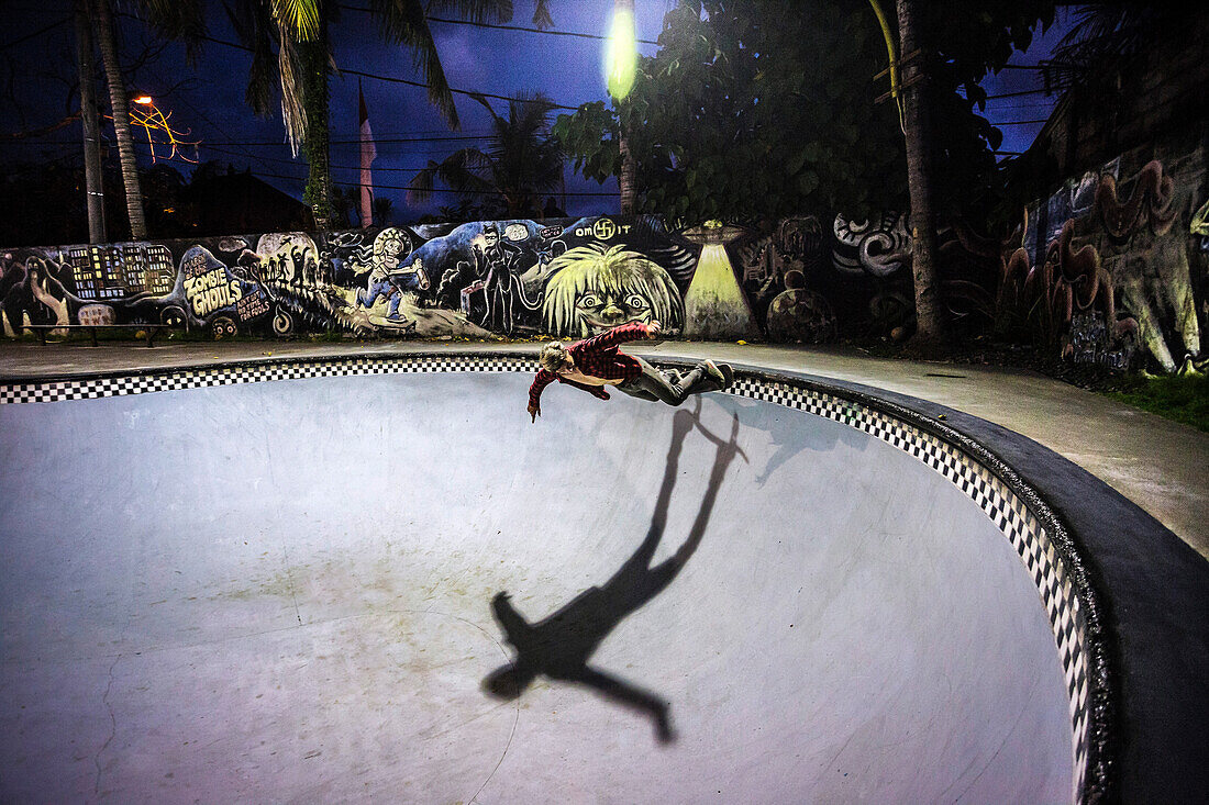 Male skateboarder riding in illuminated skate park at night, Jimbaran, Bali, Indonesia