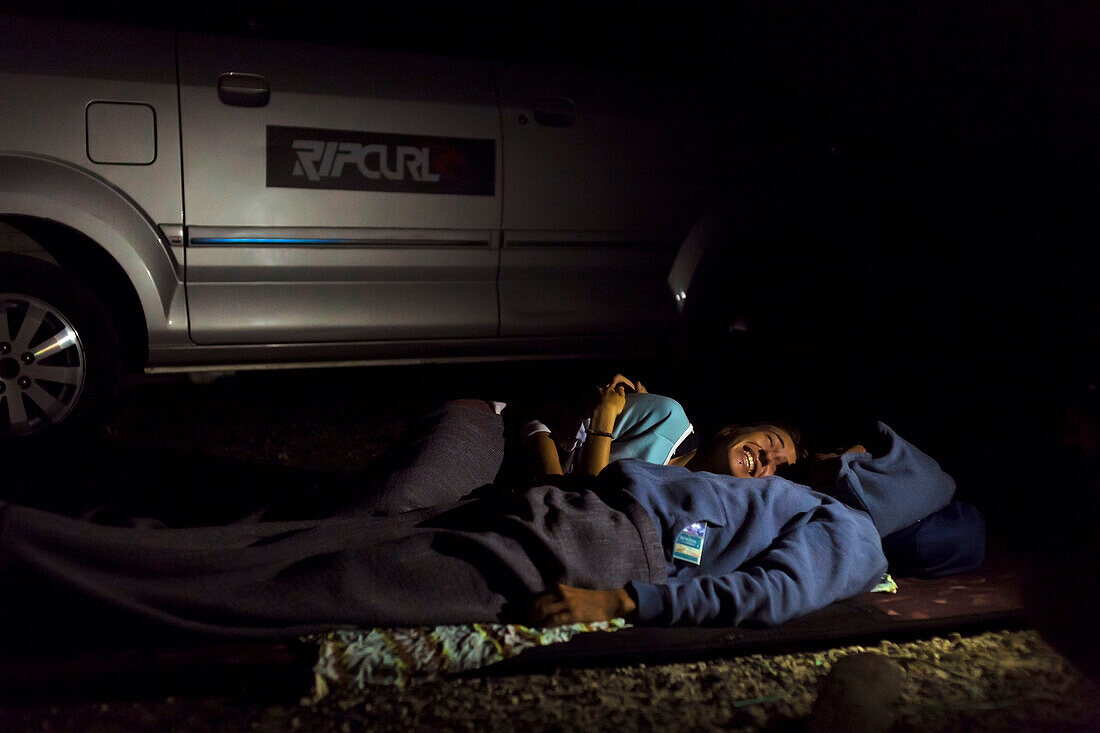 Couple sleeping near car at night, Batukaras, Java, Indonesia