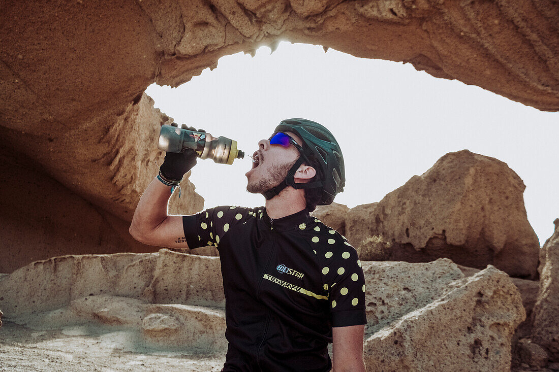Mountain bike cyclist drinks water during ride in desert, Tenerife, Canary Islands, Spain