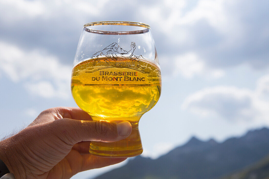 A Glass of craft beer (Biere du Mont Blanc) hold to the sky. This is at the end of the Tour du Mont Blanc, a classic trekking around the highest peak of the Alps, that goes through France, Italy and Switzerland.