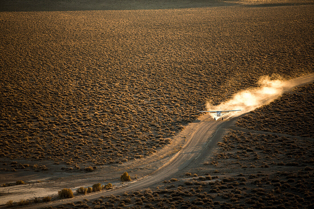 A prop plane raises a dust cloud as it travels down a High Mesa road.