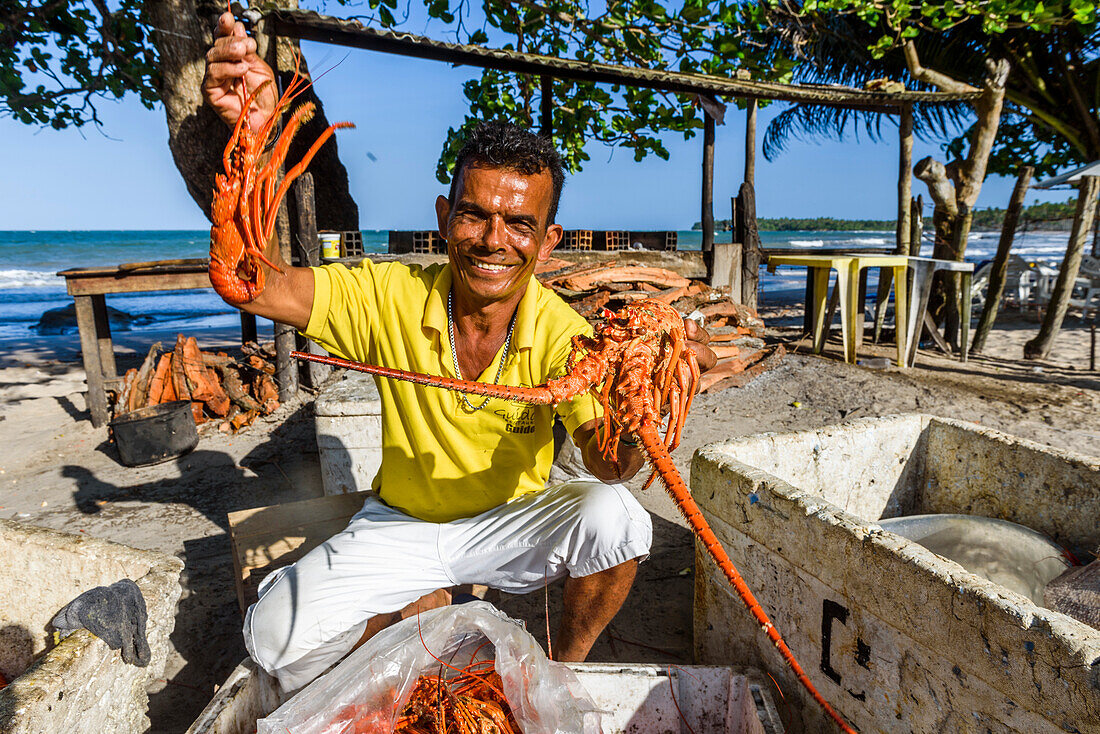 Smiling local restaurant owner showing fresh lobsters, Boipeba Island, south Bahia, Brazil