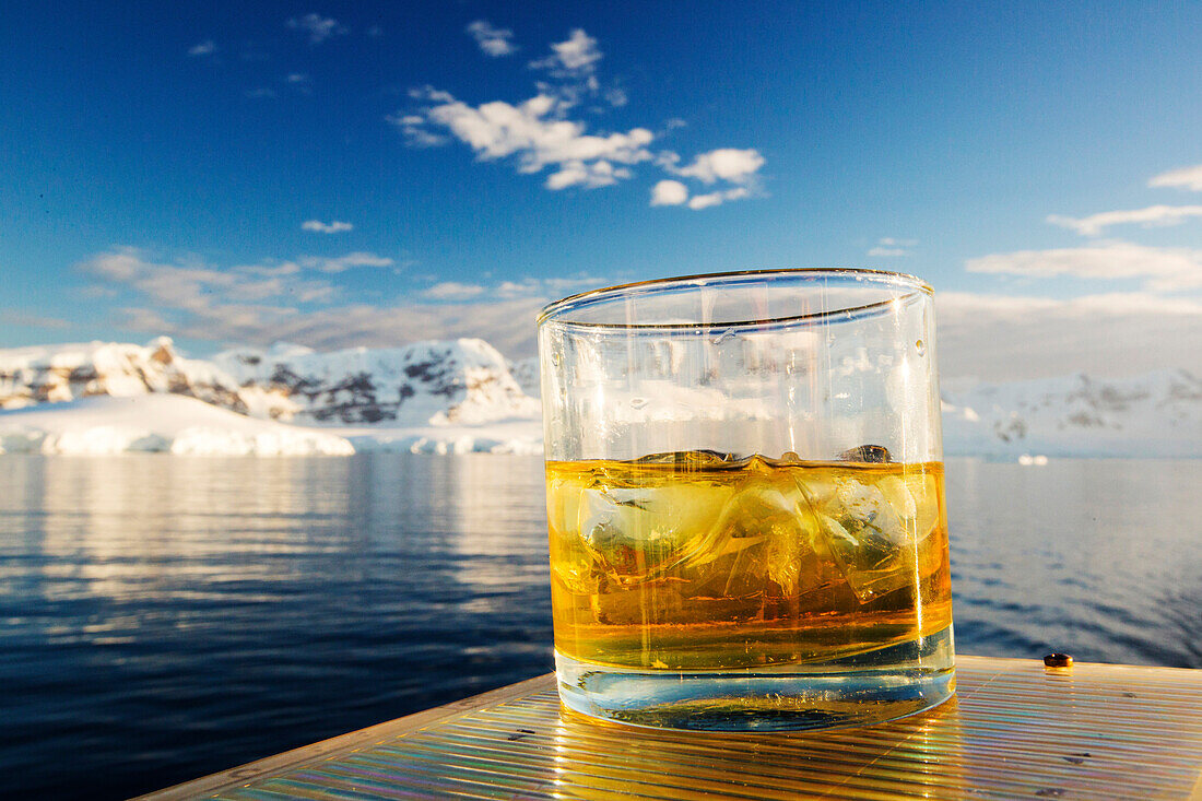 A Scotch on the rocks with 100,000 year old glacier ice on the deck of the Akademik Sergey Vavilov, an ice strengthened ship on an expedition cruise to Antarctica, off the Antarctic peninsula at the Gerlache Strait. The Antarctic peninsula is one of the m