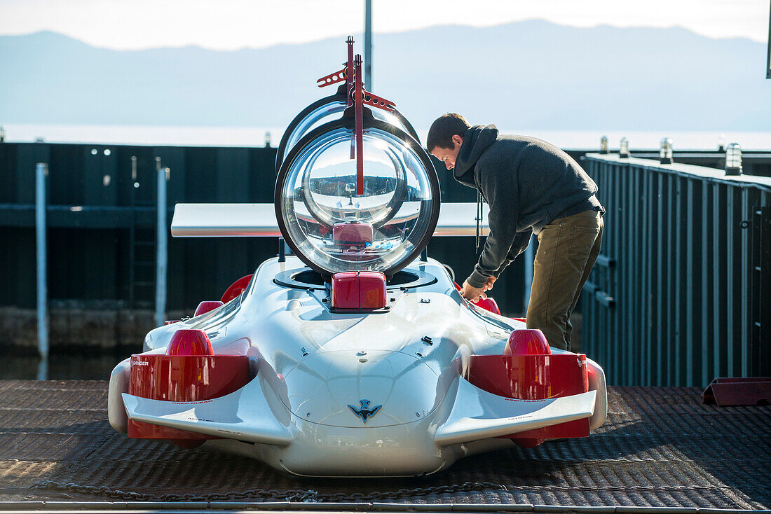 Young man preparing prototype personal two-man submarine for test dive, Homewood Marina, Lake Tahoe, California, USA