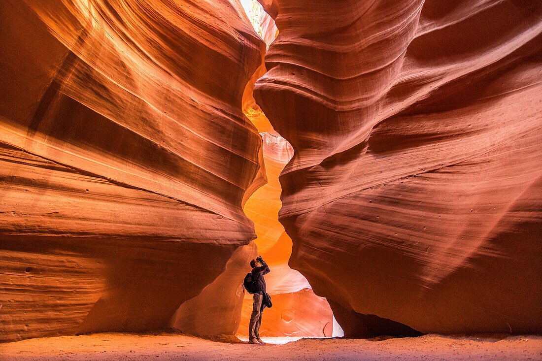 Photographer aims camera up at the glowing red rocks.