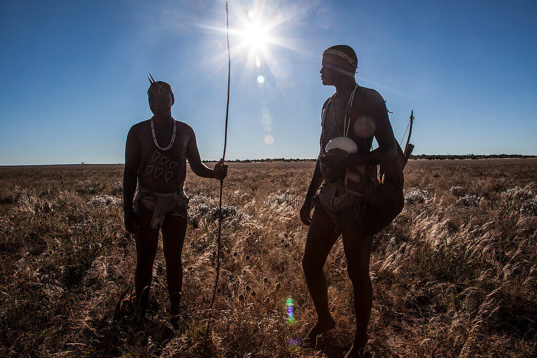 Photograph of two members of San people walking through underbrush in Kalahari Desert, Botswana