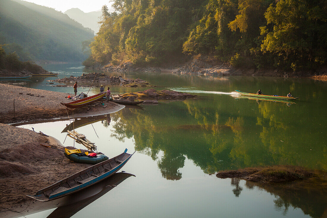 Robert Hahn stands with fishermen on the shore of the Nam Ou River at sunset as a motorboat speeds past at Ban Sop Khip, Laos, a village that will be completely inundated by Nam Ou River Dam #5.