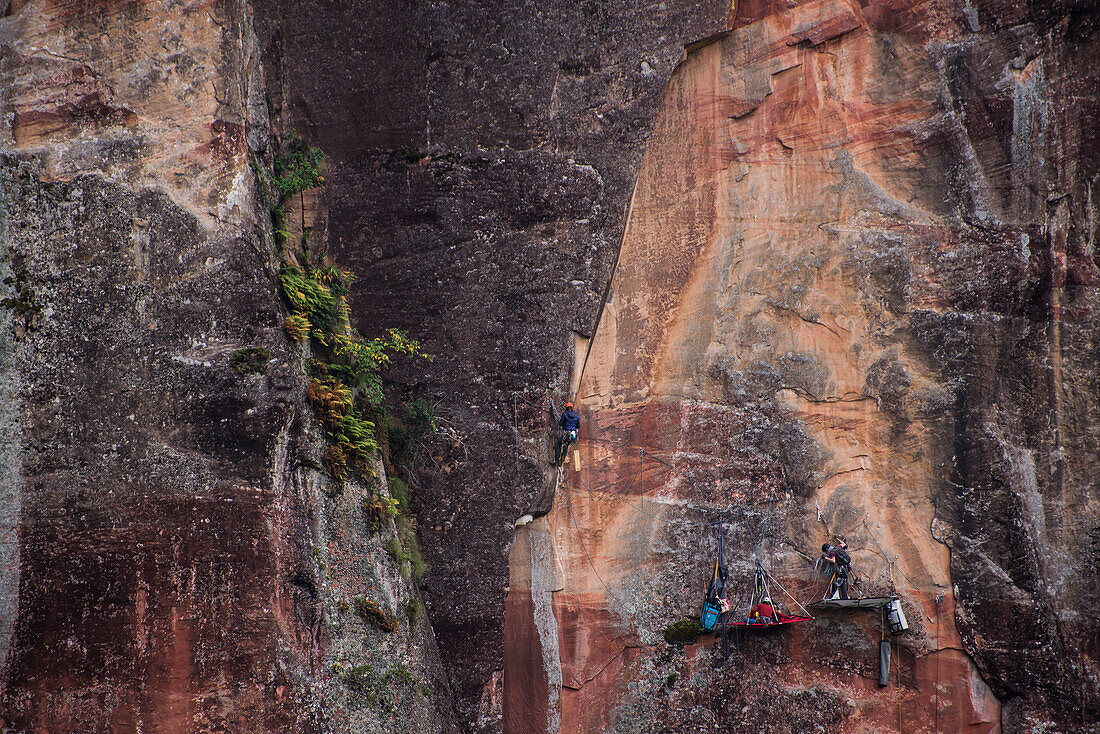 Distant view of adventurous rock climber climbing challenging cliff, Liming, Yunnan Province, China