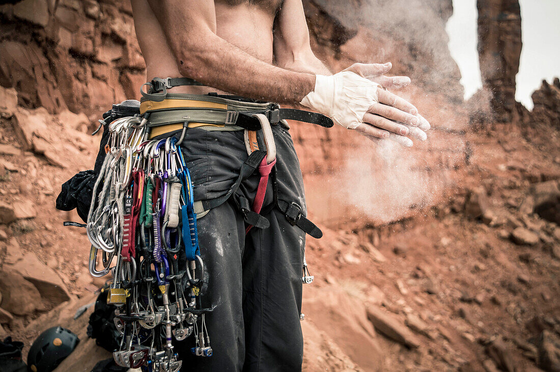 Mid section shot of rock climber applying chalk on hands, Moab, Utah, USA