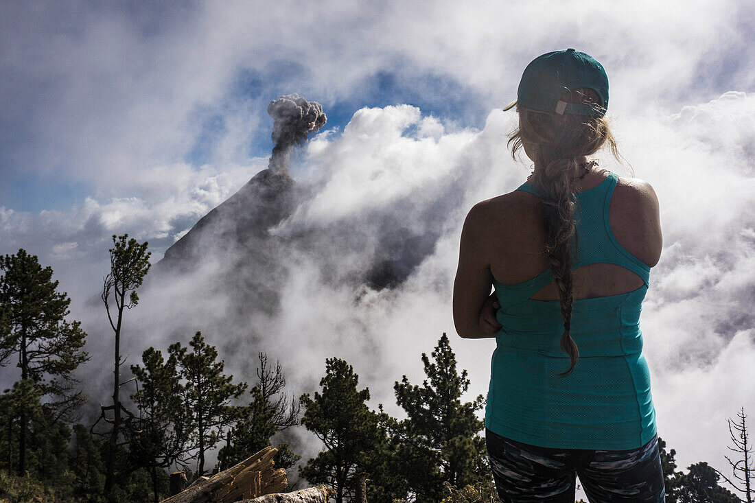 Rear view shot of young female hiker looking at view of Fuego Volcano, Guatemala