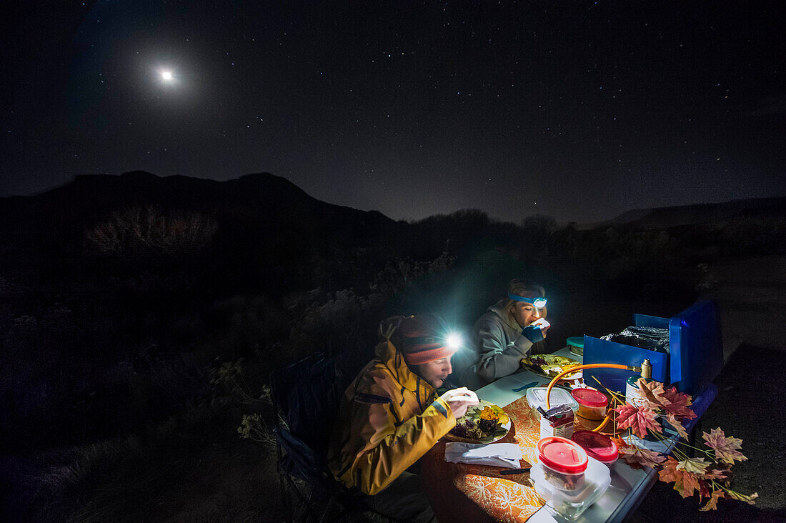 Young couple eating Thanksgiving dinner while camping in Zion National Park at night, Utah, USA