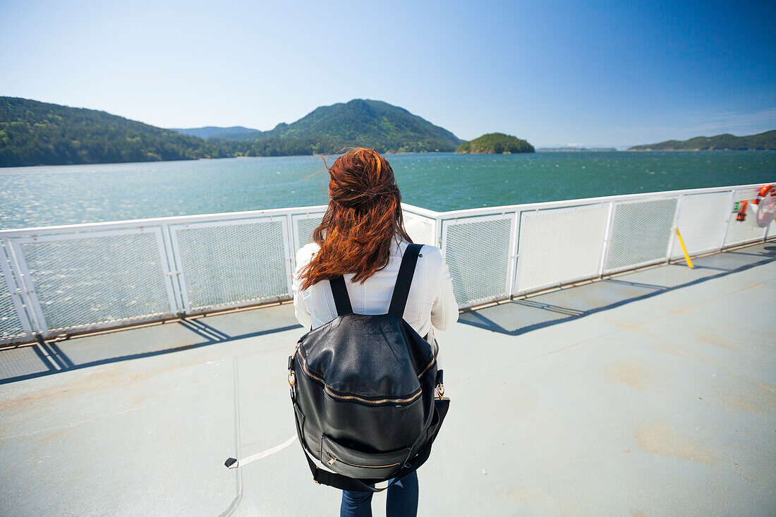 Rear view of woman with backpack standing on ferry deck