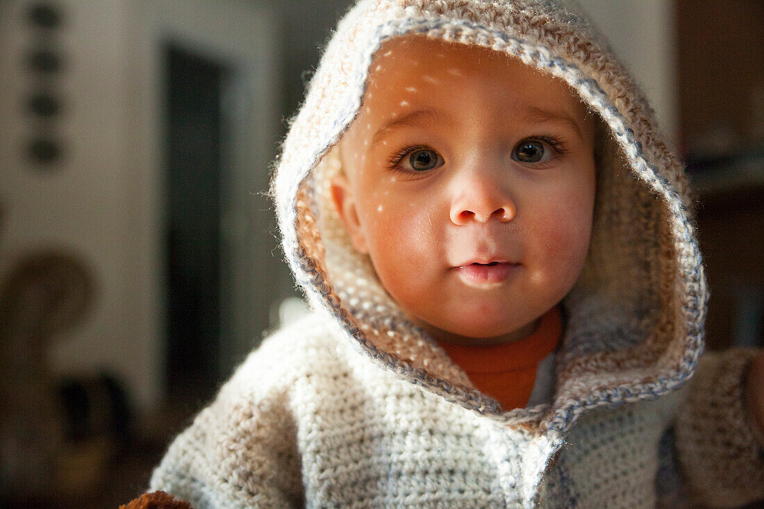 Headshot portrait of baby boy in hooded knit sweater