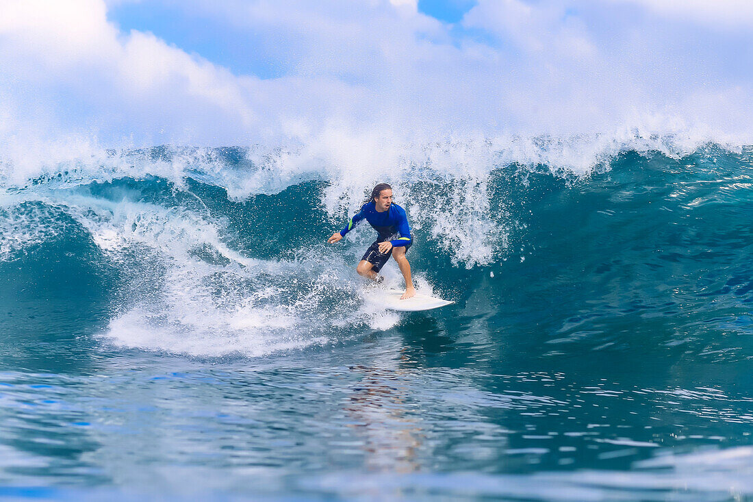 Young man riding wave on surfboard in sea