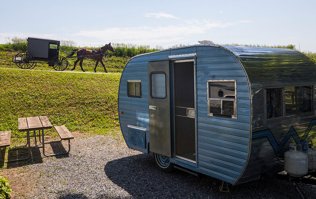 Single Amish carriage moving down road in the background and camper trailer in the foreground, Intercourse, Lancaster County, Pennsylvania, USA