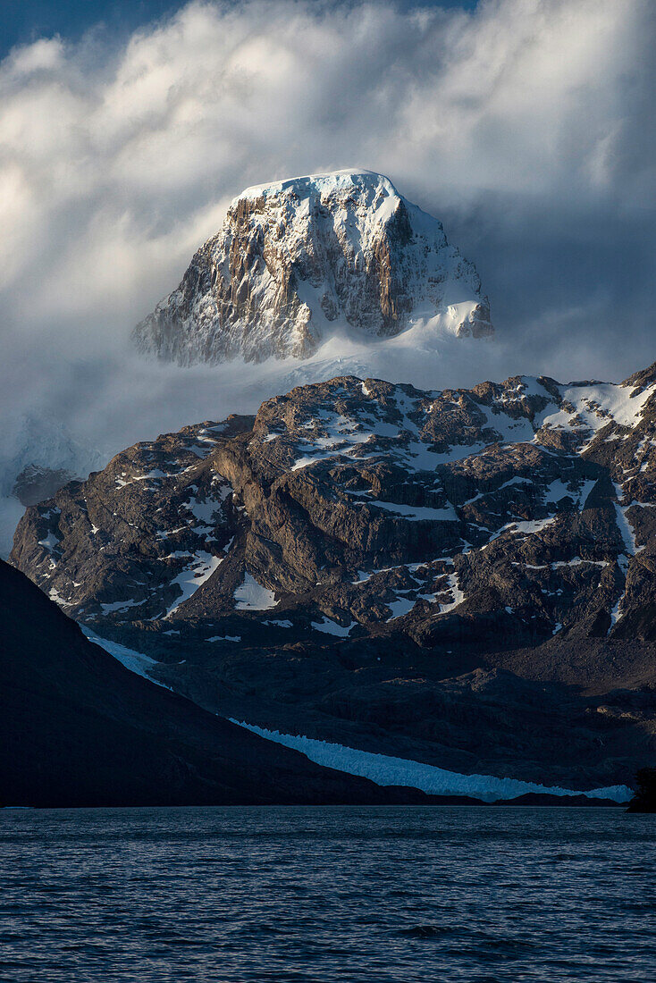 Majestic natural scenery of mountain cloaked with clouds on coastline, Patagonia