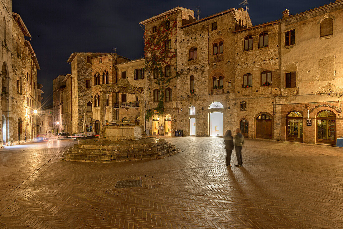 Tourists in the square of San Gimignano at night. Italy, Tuscany, Siena district.